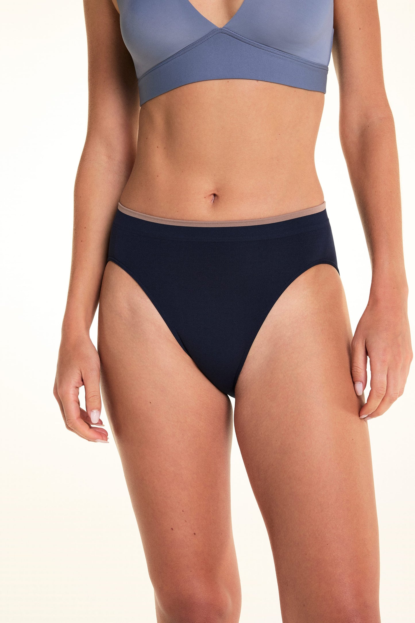On a light studio backdrop, Alexis wears the Seamless Brief in Navy. The front view highlights the high-rise silhouette, smooth seamless construction, and contrasting trim at the waistband.  sizing: Alexis wears size Small