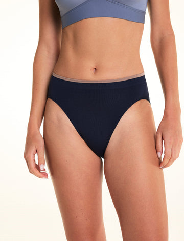 On a light studio backdrop, Alexis wears the Seamless Brief in Navy. The front view highlights the high-rise silhouette, smooth seamless construction, and contrasting trim at the waistband.  sizing: Alexis wears size Small