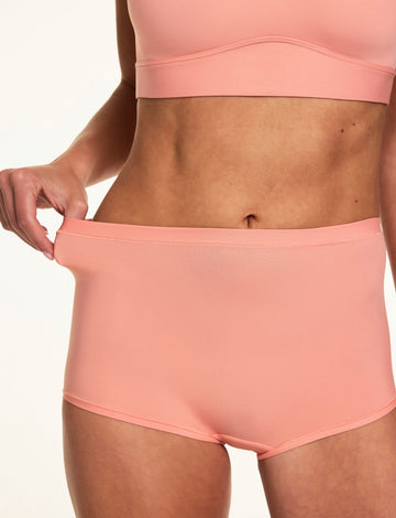 In a close-up studio image, Gianna wears the Bliss Boyshort in Cabana with the matching Bliss bralette, gently pulling the waistband to highlight the soft stretch fabric and smooth finish.  sizing: Gianna wears size Small