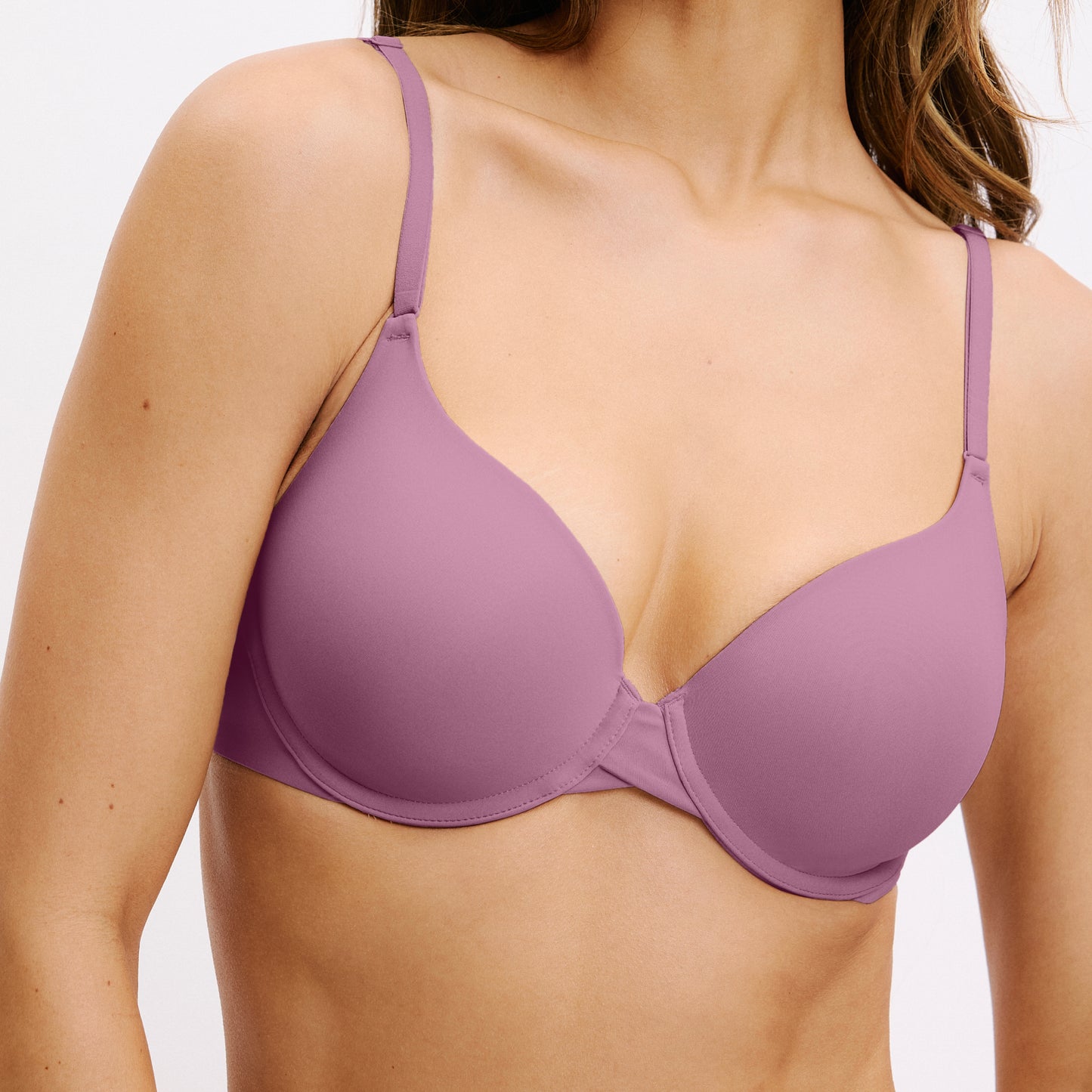 In a white studio setting, Darion wears the Base Bra in Mirage, shown in a close-up highlighting the smooth molded cups and clean neckline.