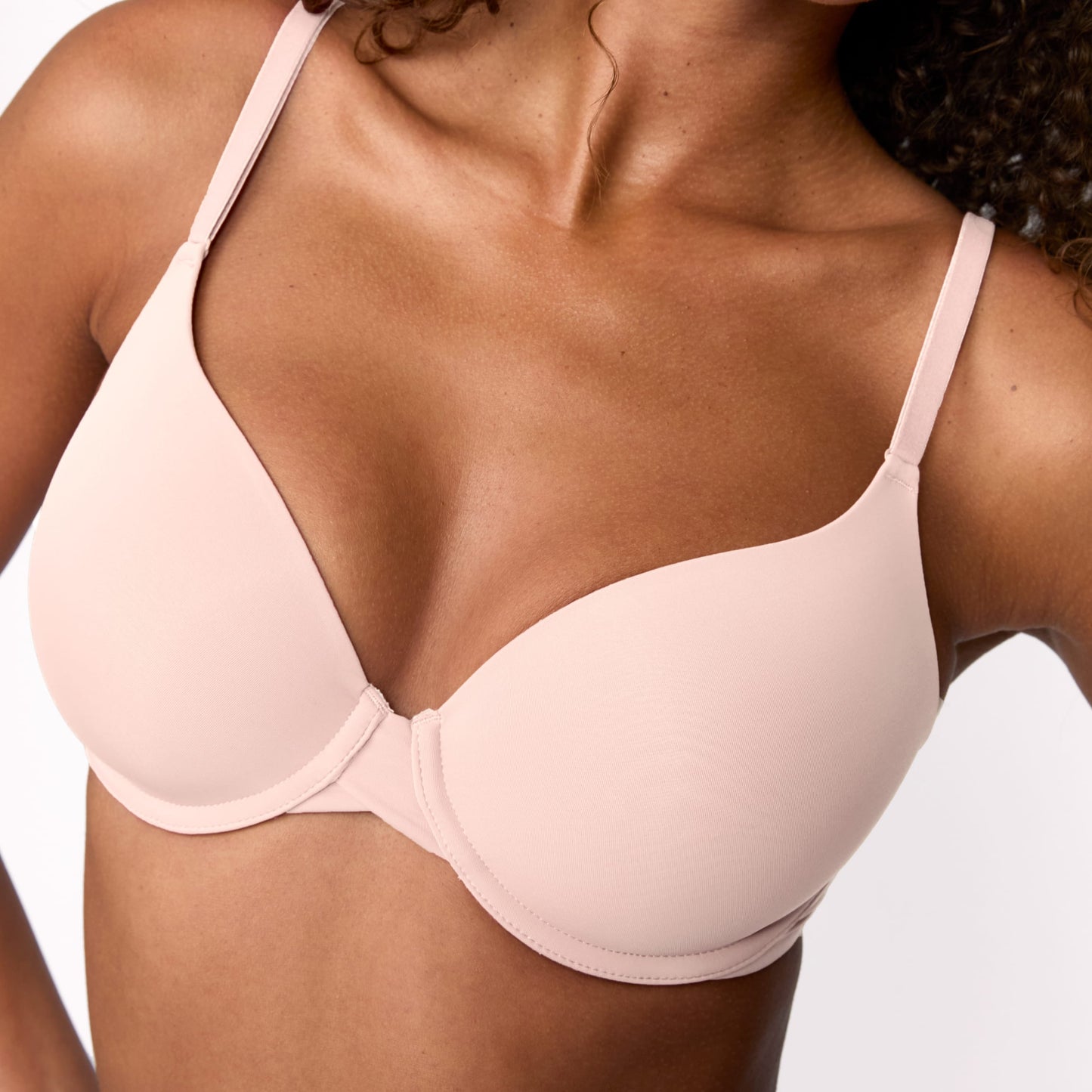 On a light studio backdrop, Courtney wears the Base T-Shirt Bra in Rose, shown in a close-up. The bra features smooth molded cups, adjustable straps, and an underwire for support.
