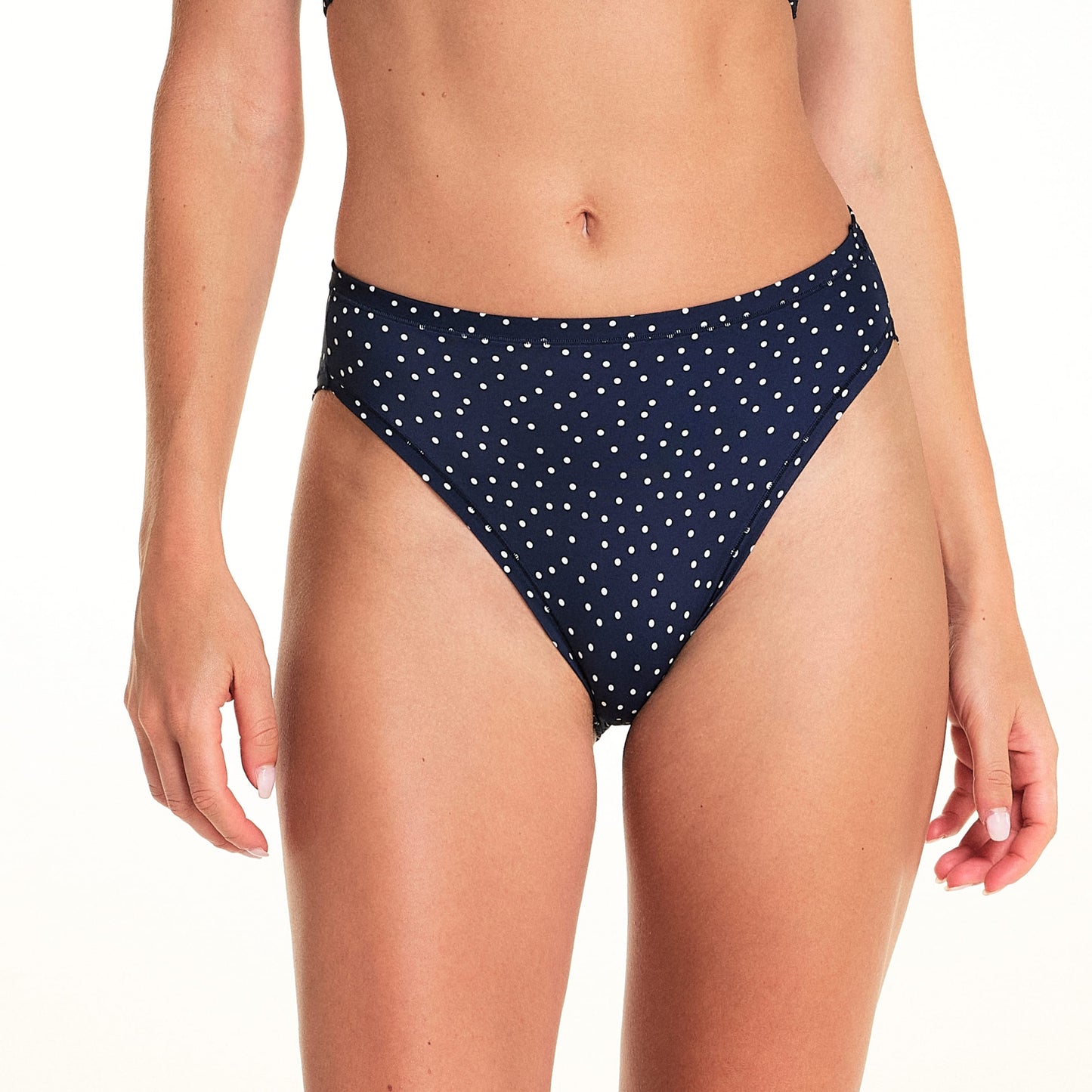 On a light studio backdrop, Alexis wears the Bliss French Cut in Navy Dot. The cropped image highlights the mid-rise waist, high-cut leg openings, and allover white dot print.