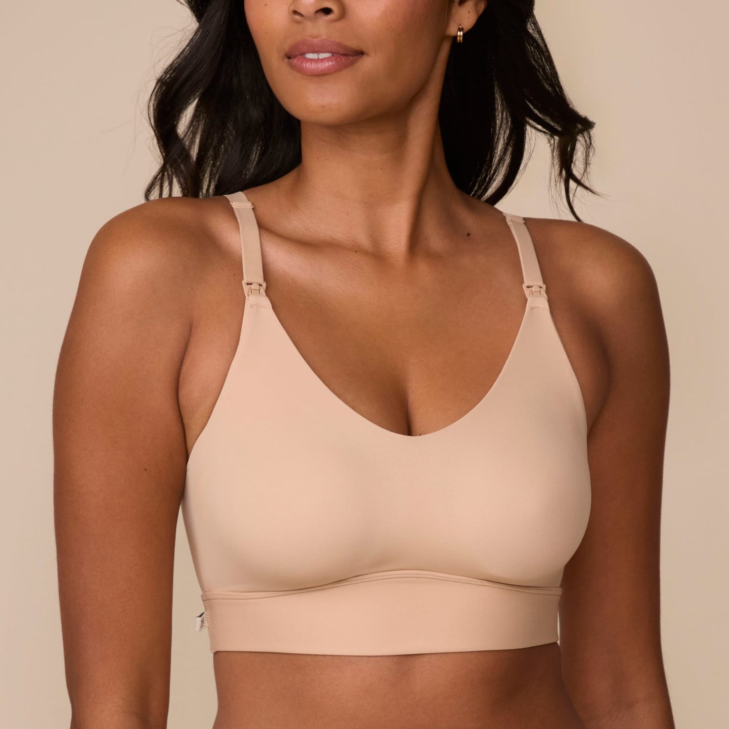 On a neutral studio backdrop, Victoria wears the Bliss Nursing Bralette in Beige. The close-up view highlights the scoop neckline, nursing clips, wireless design, smooth fabric, and wide supportive underband.