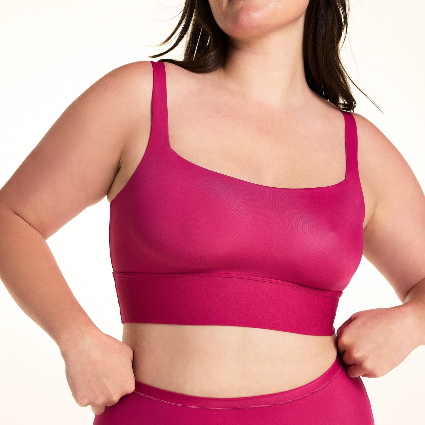 On a light studio backdrop, Alessandra wears the Bliss Square Neck Bralette in Winterberry. The cropped image highlights the square neckline, smooth fabric, wide comfort band, and supportive straps.