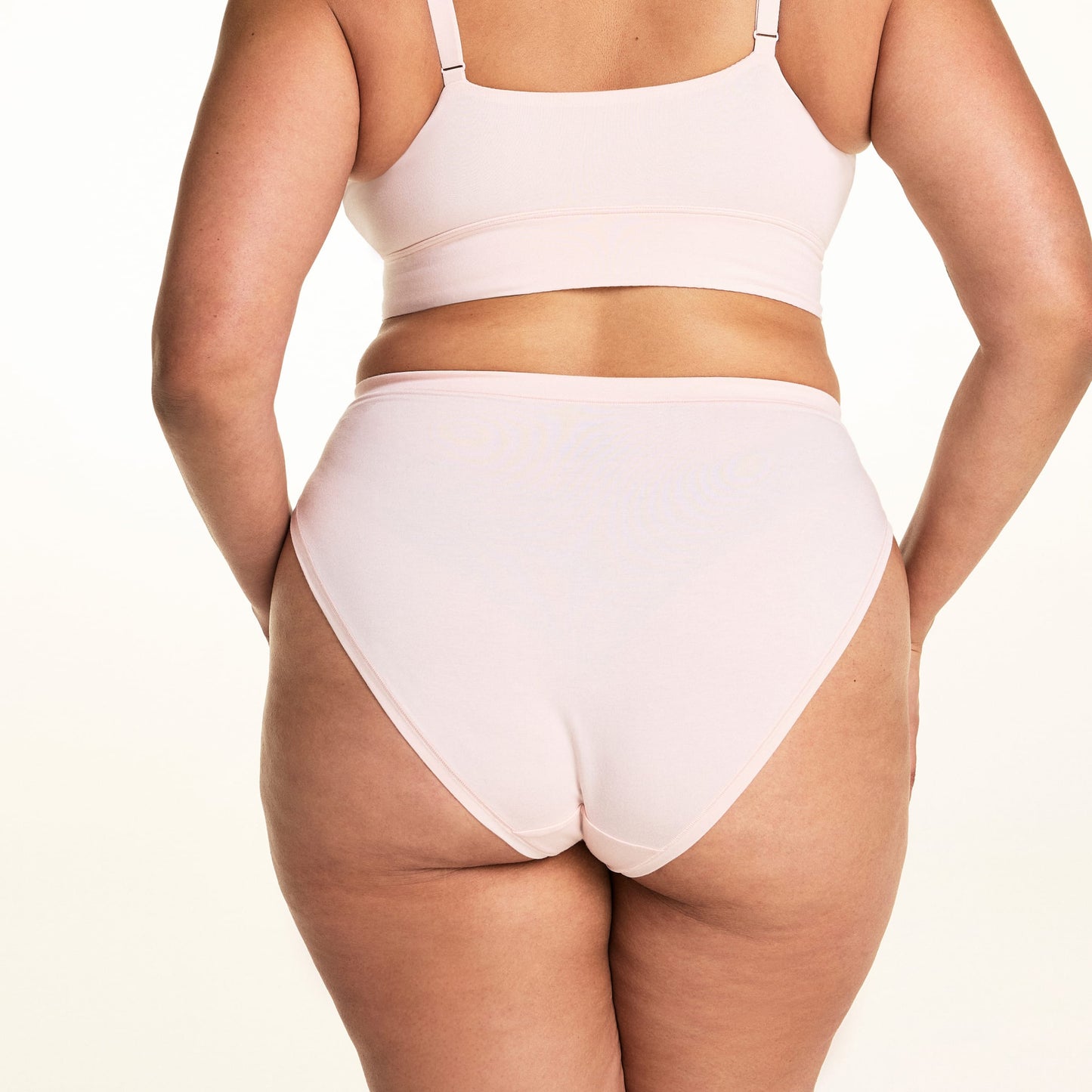 On a light studio backdrop, Jennifer wears the Cloud Cotton French Cut in Dogwood. The back view highlights the smooth waistband, full back coverage, and soft cotton fabric.