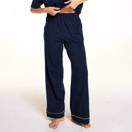 In a close-up studio image, Meagan wears the Perfect Pima Pants in Navy, highlighting the elastic waistband and wide-leg silhouette with contrast piping at the hem.