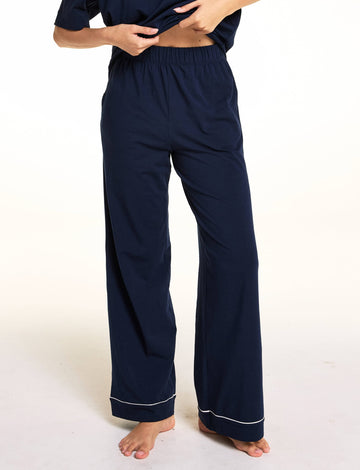 In a close-up studio image, Meagan wears the Perfect Pima Pants in Navy, highlighting the elastic waistband and wide-leg silhouette with contrast piping at the hem.