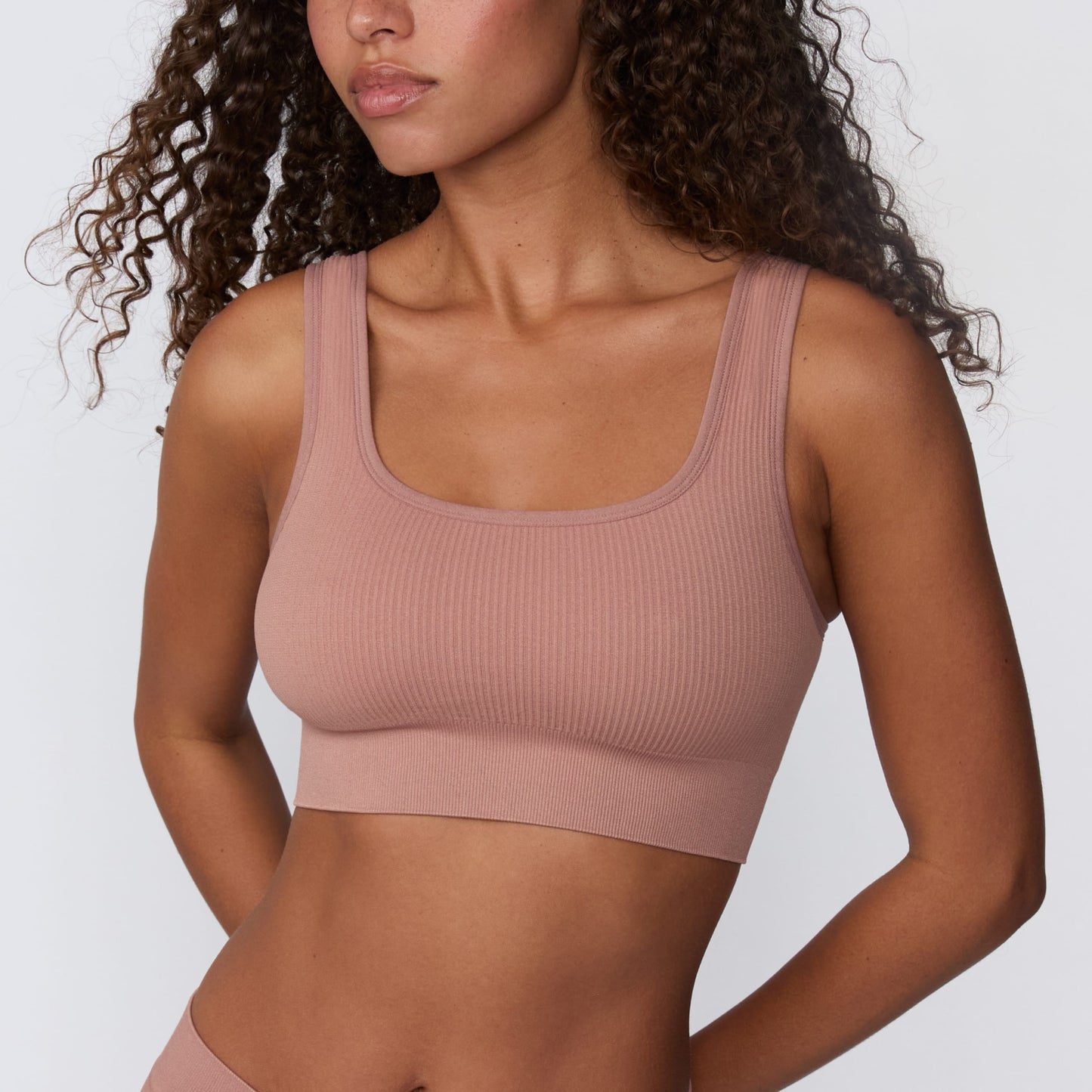 In a studio setting, Courtney wears the Ribbed Seamless Scoop Bralette in Plum. A close-up front view highlights the scoop neckline, wide straps, supportive underband, and ribbed texture.