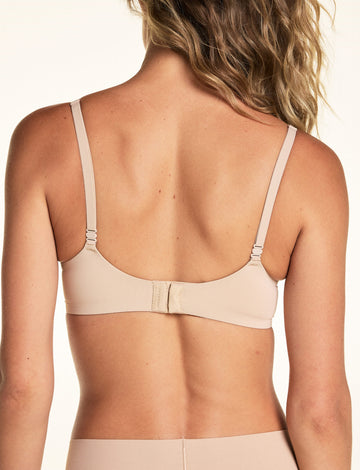 On a light studio backdrop, Alexis is shown from the back wearing the Base Picot T-Shirt Bra in Beige. The image highlights the adjustable straps and back hook-and-eye closure.