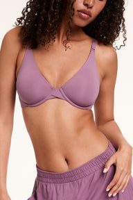 In a studio setting, Courtney wears the Base Unlined Bra in Mirage, paired with matching lounge pants. The unlined underwire cups and soft microfiber fabric provide lightweight support, with front-adjusting straps visible. sizing: Courtney wears size 32D