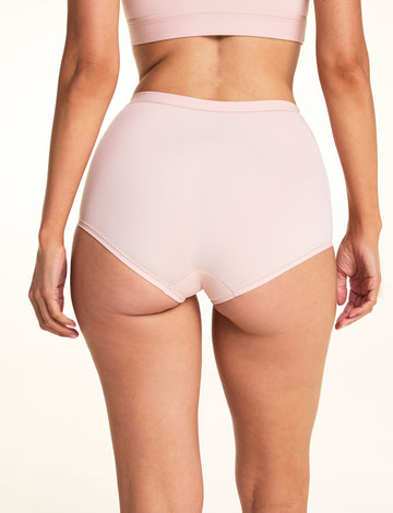 On a light studio backdrop, Meagan wears the Bliss Boyshort in Ember Rose, shown from the back to highlight the full-coverage fit, smooth fabric, and clean leg openings.