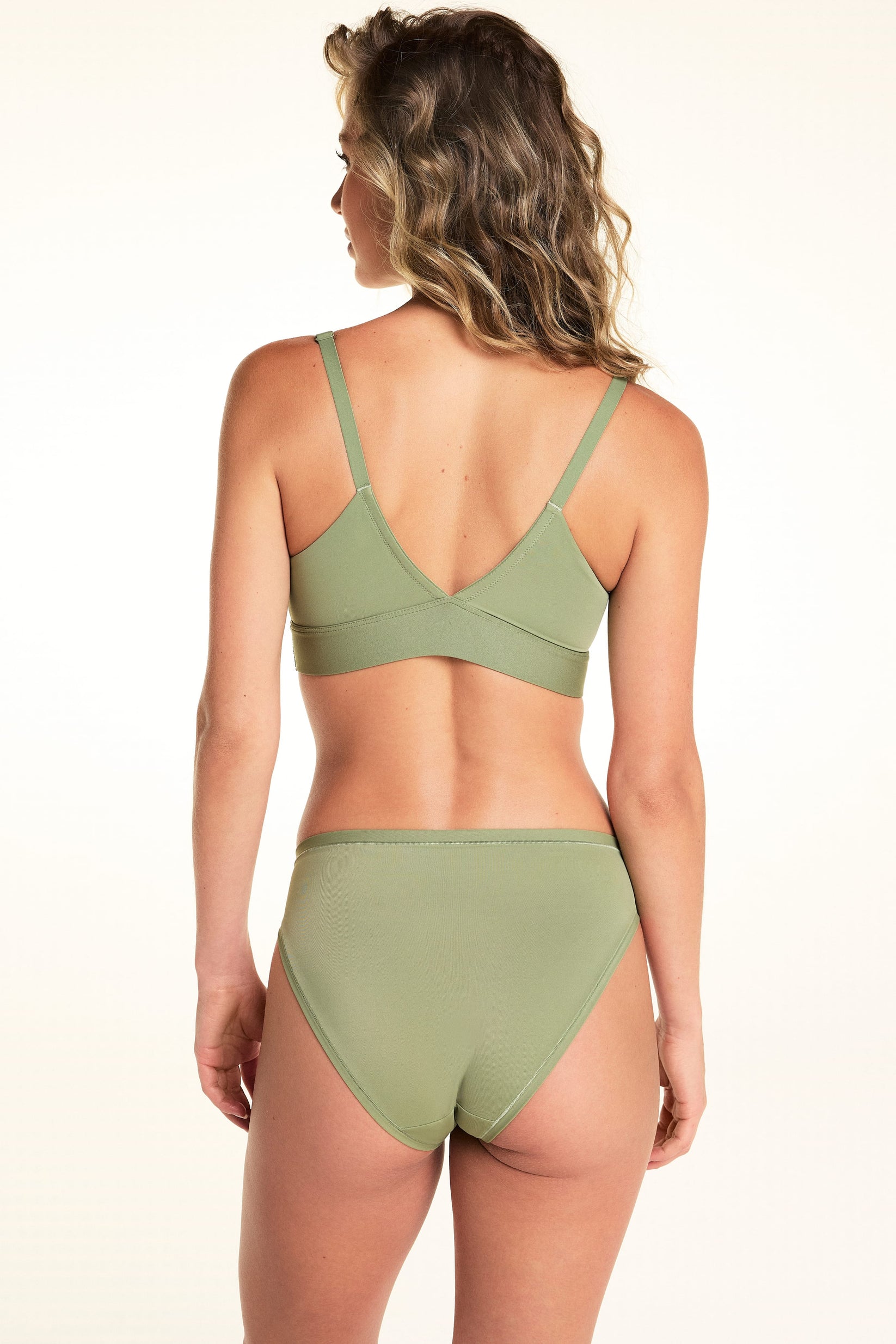 Back view of Alexis wearing the Bliss French Cut Brief in Dill. The brief features a high-rise waist, full back panel, and a smooth microfiber finish.