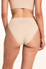 Against a white studio backdrop, Meagan wears the Bliss French Cut underwear in Beige, showing the back coverage and smooth waistband in a close-up back-facing pose.