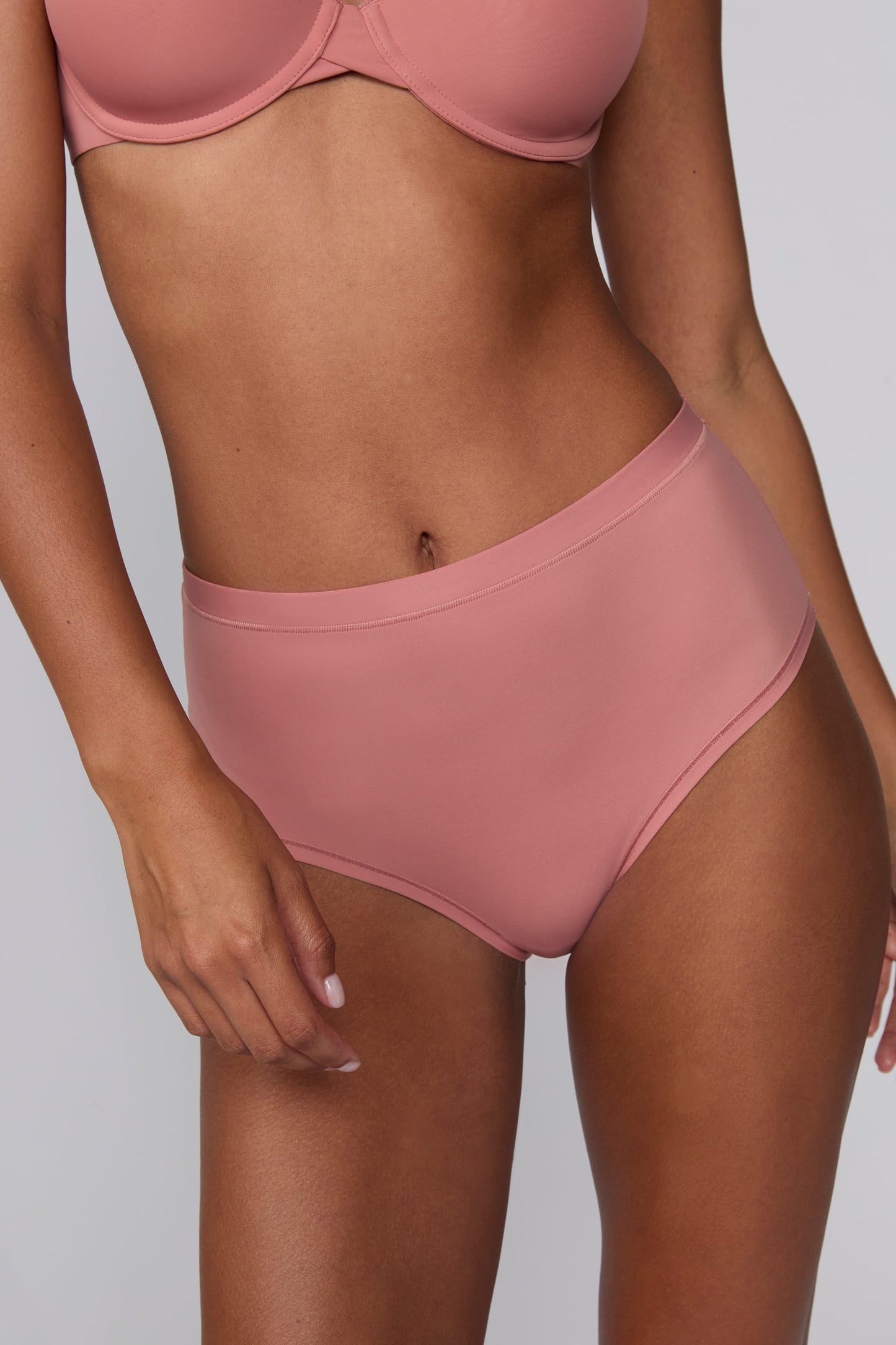 In a studio setting, Courtney wears the Bliss Highwaist Brief in Cinnamon. A close-up front view highlights the smooth fabric, high-rise waistband, and clean finish.
