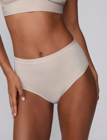 In a studio setting, Courtney wears the Bliss Highwaist Brief in Pebble. A close-up front view highlights the smooth fabric, high-rise waist, and clean finish.