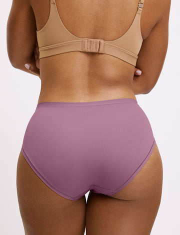 In a studio setting, Amber wears the Bliss High Waist underwear in Mirage paired with a matching bra, shown from the back. The underwear features a high-rise fit, full coverage, and smooth, seamless fabric.