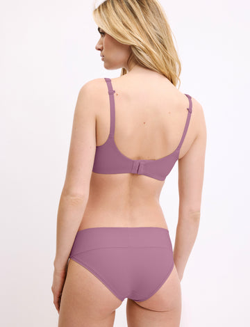 In a studio setting, a model wears the Bliss Low Rise Bikini in Mirage with a matching bra, shown from the back. The bikini features a low-rise fit, minimal coverage, and smooth, seamless fabric.