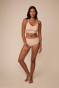 On a neutral studio backdrop, Victoria wears the Bliss Nursing Bralette in Beige with matching underwear. The full-body view showcases the bralette’s wireless construction, nursing clips, smooth silhouette, and wide comfort band.