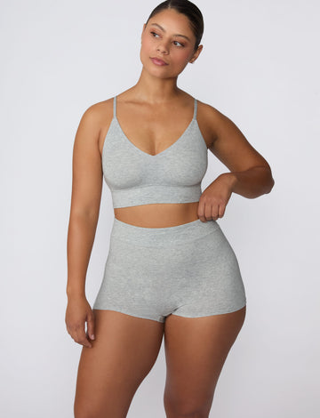 On a light gray studio backdrop, India wears the Cloud Cotton Boyshort in Heather Grey with the matching bralette. The full-body front view showcases the high-rise waistband, smooth fit, and longer leg coverage.