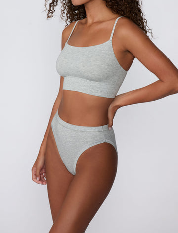 In a studio setting, Courtney wears the Cloud Cotton French Cut Brief in Heather Grey with the matching Cloud Cotton Thin Strap Bralette. The angled view highlights the French-cut silhouette, mid-rise fit, and soft cotton fabric.
