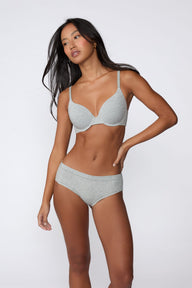 In a studio setting, Amber wears the Cloud Cotton Hiphugger in Heather Grey with the matching bra. The full-body front view highlights the low-rise waistband, hiphugger silhouette, and soft cotton fabric.