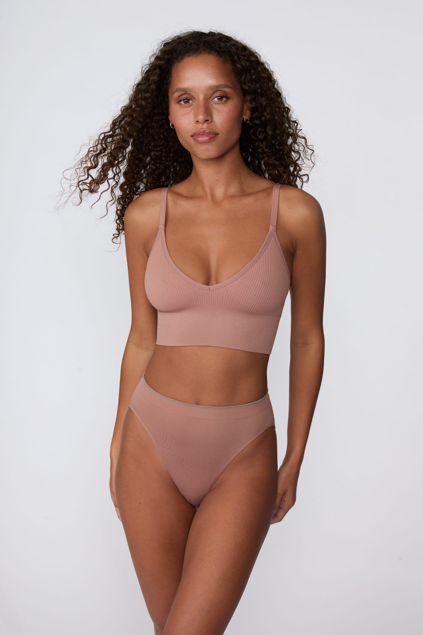 In a studio setting, Courtney wears the Smooth Seamless Brief in Plum with the matching Seamless Scoop Bralette in Plum. The front view highlights the high-leg cut, smooth finish, and comfortable coverage.