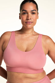 On a light neutral backdrop, Jennifer wears the Bliss Scoop Adjustable Bralette in Cinnamon. The close-up highlights the scoop neckline, wide adjustable straps, and smooth microfiber fabric with wireless support.