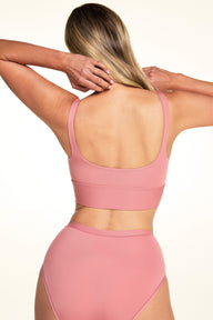 On a light neutral backdrop, Meagan is shown from the back wearing the Bliss Squareneck Bralette in Cinnamon with matching underwear. The image highlights the scoop back, thin straps, and longline wireless band.