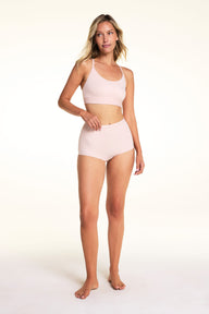 On a light studio backdrop, Meagan wears the Bliss Boyshort in Ember Rose with the matching bra. The full-body image highlights the mid-rise waist, full-coverage silhouette, and coordinated set.