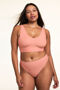 In a studio setting, Alana wears the Bliss Thong in Cabana with the matching Bliss bralette, showcasing the low-rise silhouette, minimal coverage fit, and smooth, soft fabric.  sizing: Alana wears size Large