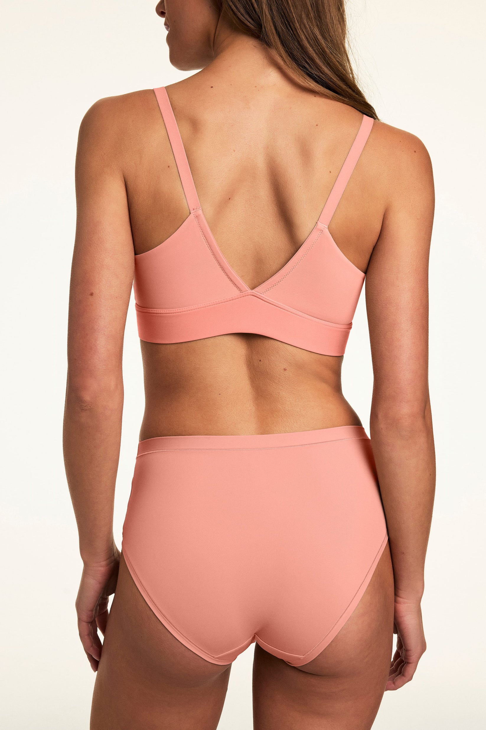 From the back, Gianna wears the Bliss Triangle Bralette in Cabana with matching underwear, featuring adjustable straps, a V-back design, and smooth fabric. sizing: Gianna wears size Small