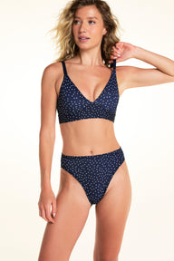 On a light studio backdrop, Alexis wears the Bliss Triangle Bralette in Navy Dot with matching Navy Dot underwear. The image highlights the plunge neckline, adjustable straps, and soft printed fabric.