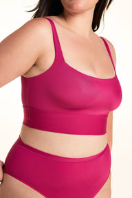 On a light studio backdrop, Alessandra wears the Bliss Square Neck Bralette in Winterberry. The close-up angled view highlights the square neckline, smooth fabric, wide comfort band, and supportive straps.