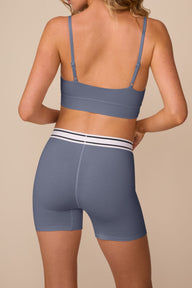 On a neutral studio backdrop, Freya wears the Cloud Cotton Retro Scoop Bralette and Cloud Cotton Retro Boxer Brief in Slate. The back view highlights the adjustable straps, smooth back band, full-coverage boxer brief silhouette, and retro-inspired striped waistband.