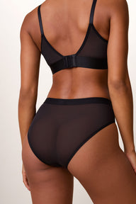 Back view of the ComfortMesh™ Highwaist Brief in Black on a light studio backdrop, showing the sheer mesh fabric and moderate back coverage.