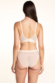 On a light studio backdrop, Laura wears the ComfortMesh™ Plunge Bra and ComfortMesh™ Highwaist Brief in Pearl. The back view highlights the sheer mesh construction of the brief, moderate back coverage, and the bra’s wide back band and adjustable straps.
