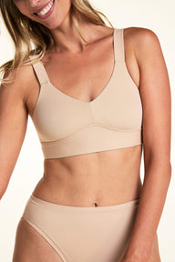 On a light neutral backdrop, Meagan wears the Bliss Smoothing Bralette in Beige with matching underwear. The close-up highlights the V-neckline, wide straps, and smooth wireless design.