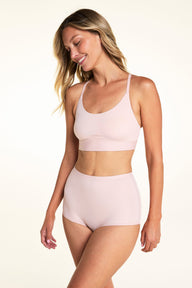On a light studio backdrop, Meagan wears the Bliss Boyshort in Ember Rose with the matching bra. The angled image highlights the smooth fabric, mid-rise waist, and full-coverage silhouette.
