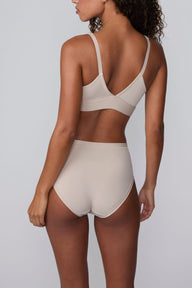 On a light gray studio backdrop, Courtney wears the Bliss Highwaist Brief in Pebble with a matching bra. A back view highlights the smooth fabric, high-rise waist, and full back coverage.