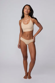 In a studio setting, Amber wears the Bliss Low Rise Bikini in Beige with the matching Bliss Bralette in Beige. The full-body front view highlights the low-rise fit, smooth fabric, and bikini silhouette.