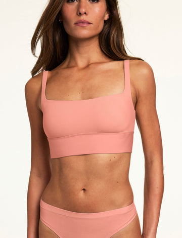 In a neutral studio setting, Gianna wears the Bliss Squareneck Bralette in Cabana with matching underwear, featuring a square neckline, wide straps, and smooth fabric.