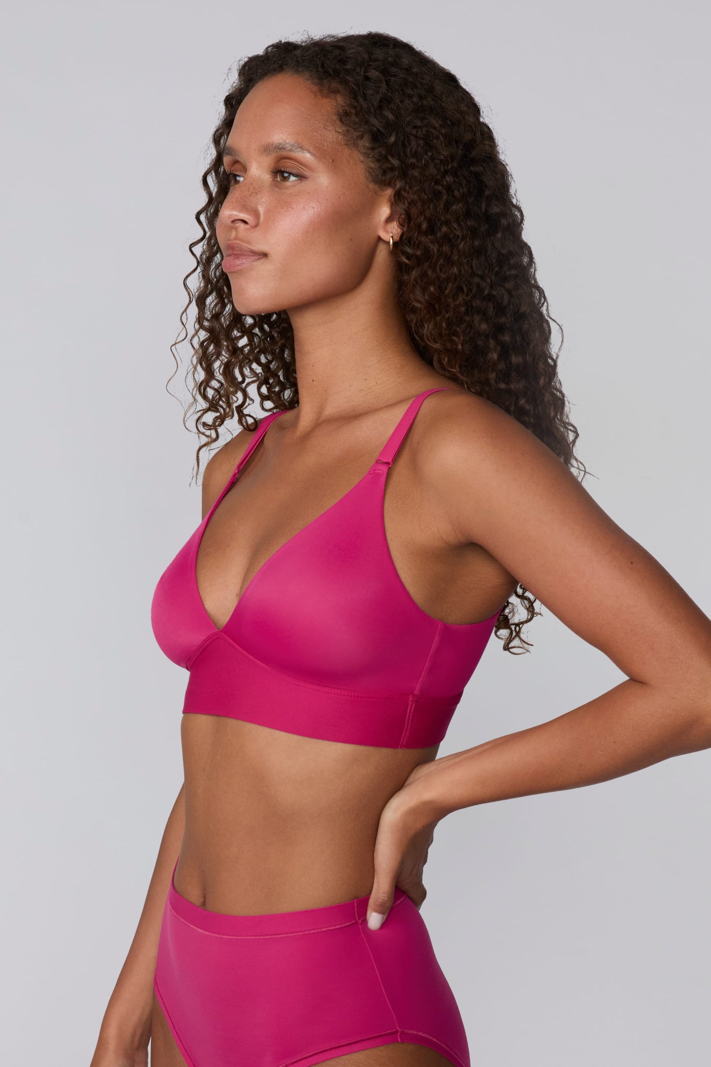 In a studio setting, Courtney wears the Bliss Triangle Bralette in Winterberry. A side-profile view highlights the smooth cups, deep V-neckline, adjustable straps, and supportive underband.