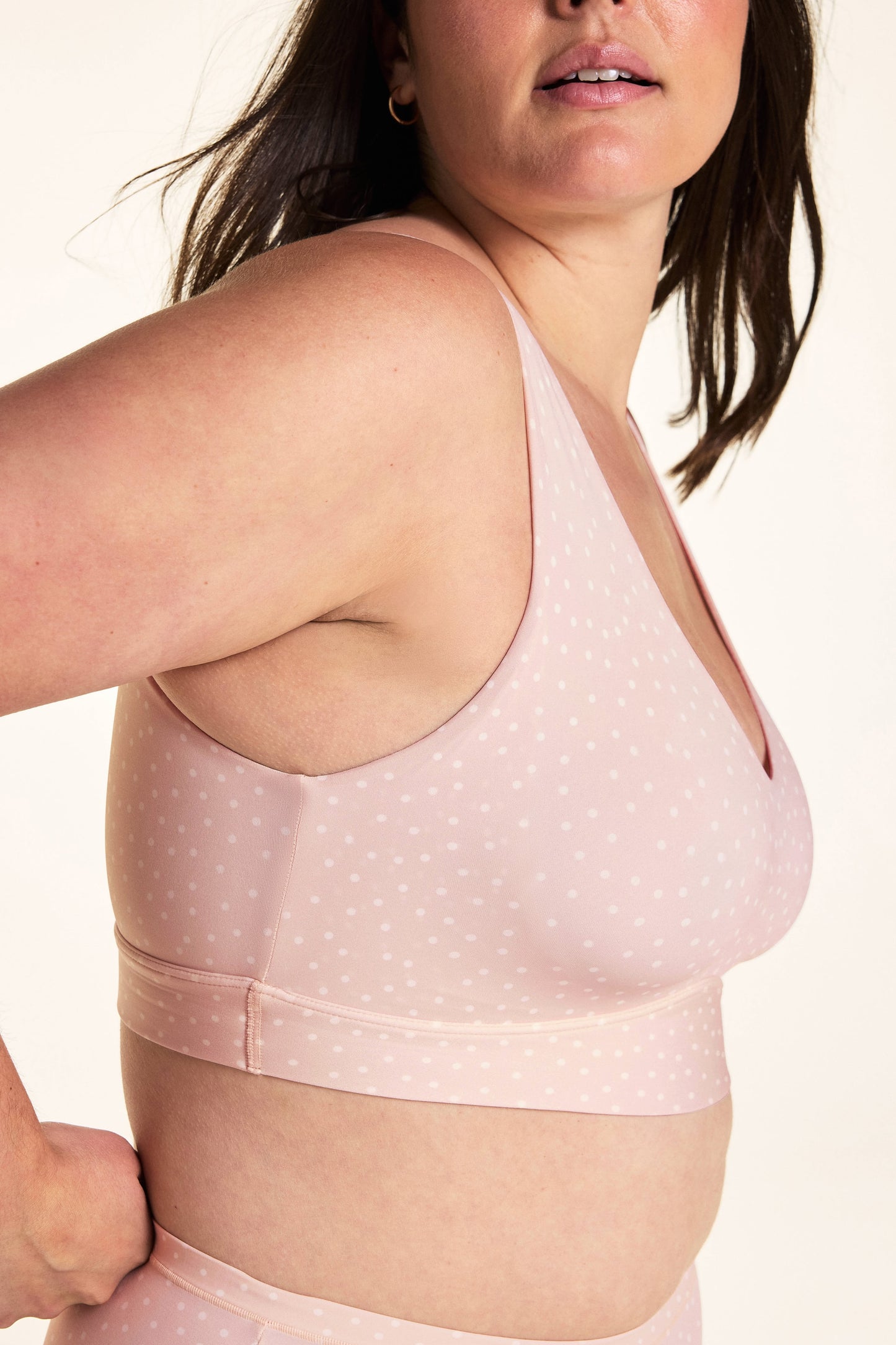 On a white studio backdrop, Alessandra wears the Bliss Bralette in Champagne Fizz from a side angle, highlighting the smooth side coverage and underbust band.