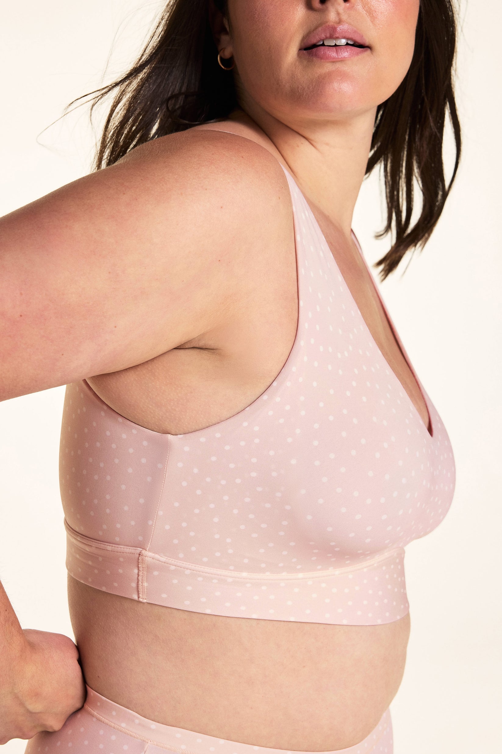 On a white studio backdrop, Alessandra wears the Bliss Bralette in Champagne Fizz from a side angle, highlighting the smooth side coverage and underbust band.