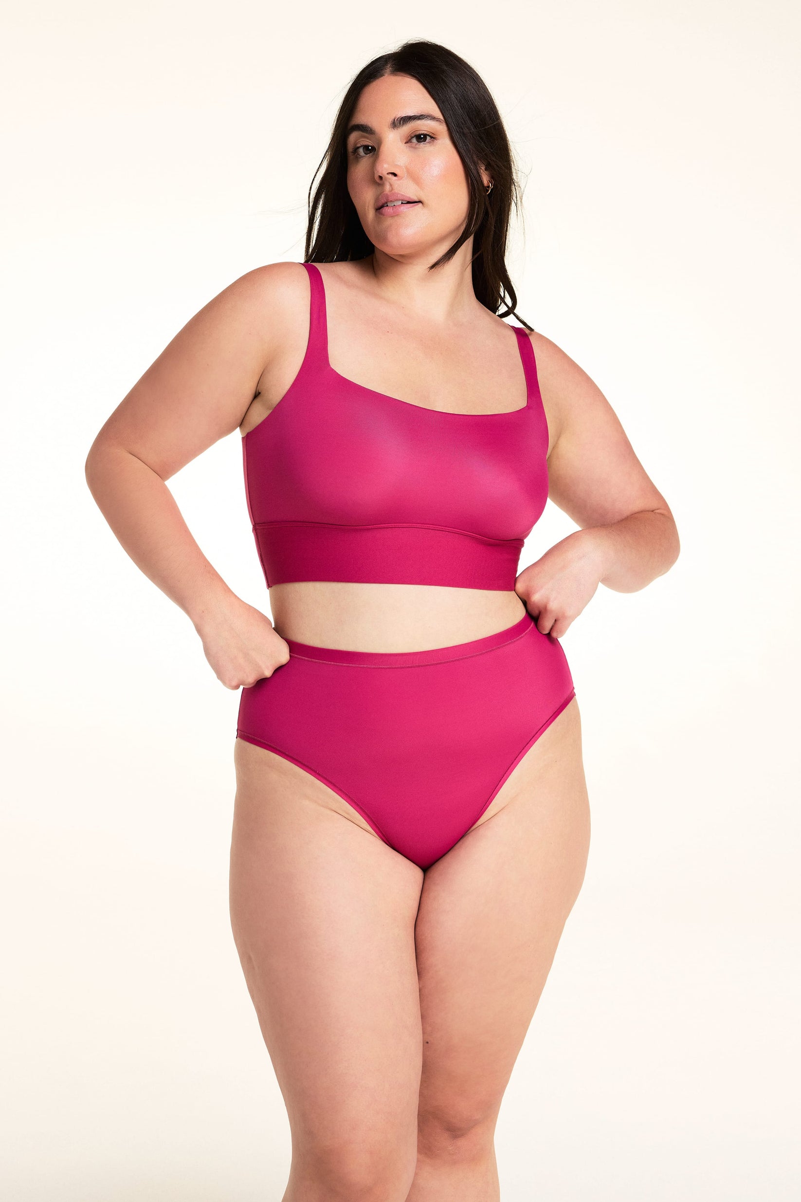 On a light studio backdrop, Alessandra wears the Bliss Square Neck Bralette in Winterberry. The full-body image showcases the square neckline, wide comfort band, smooth fabric, and supportive straps.