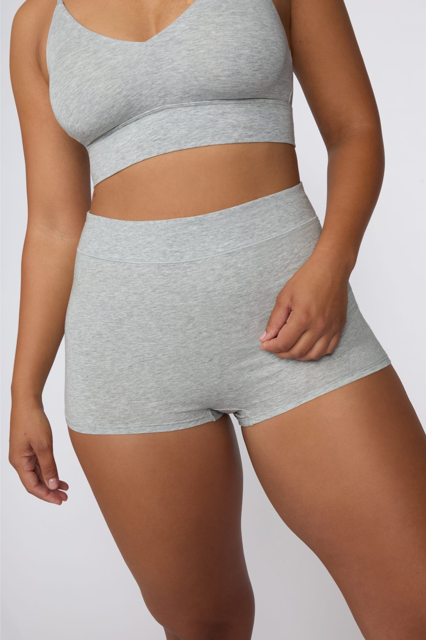 On a light gray studio backdrop, India wears the Cloud Cotton Boyshort in Heather Grey with the matching bralette. The angled front view showcases the high-rise waistband, smooth silhouette, and comfortable boyshort coverage.