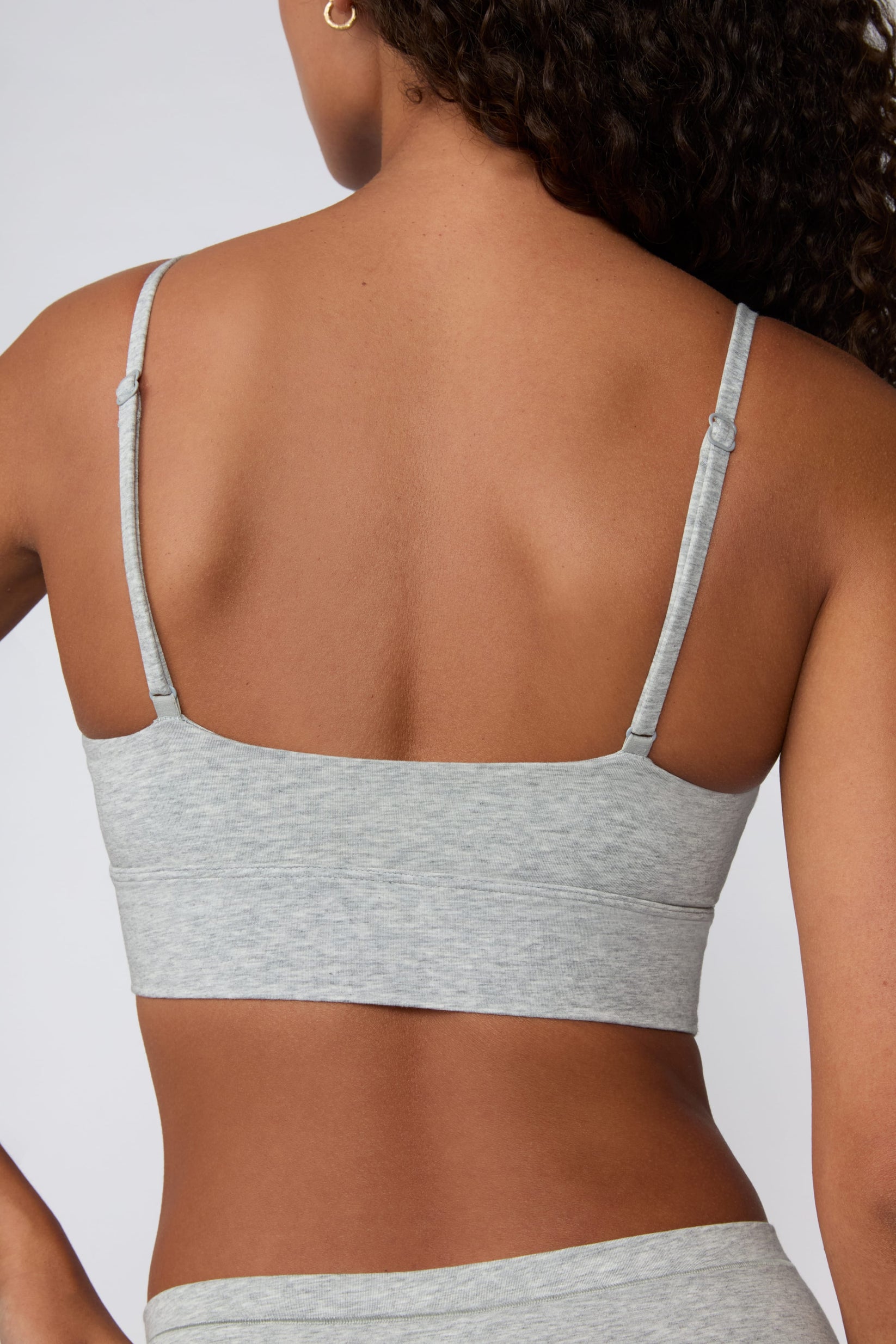 In a studio setting, Courtney wears the Cloud Cotton Thin Strap Bralette in Heather Grey with matching underwear. The back view highlights the straight-back silhouette, adjustable straps, and wide underband.