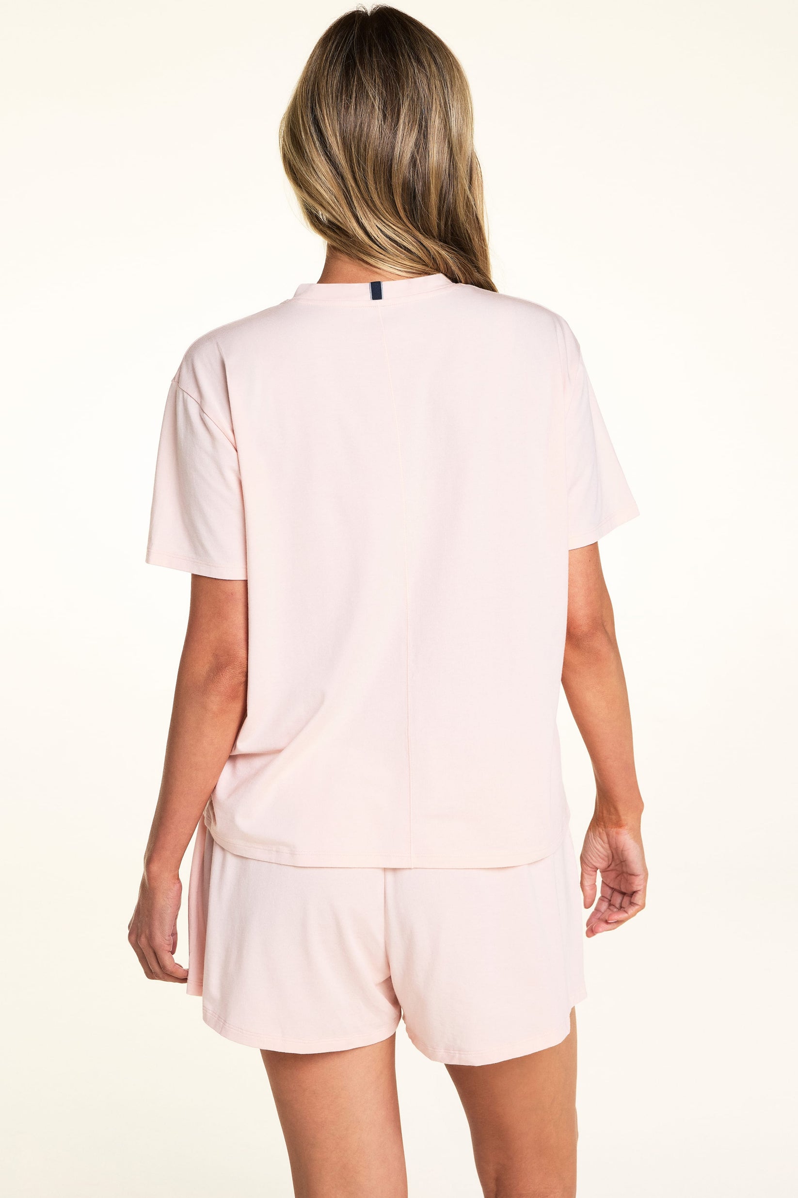 On a light studio backdrop, Meagan wears the Cloud Cotton Tee in Dogwood with matching Dogwood sleep shorts. The back view highlights the relaxed fit, short sleeves, and soft cotton fabric.