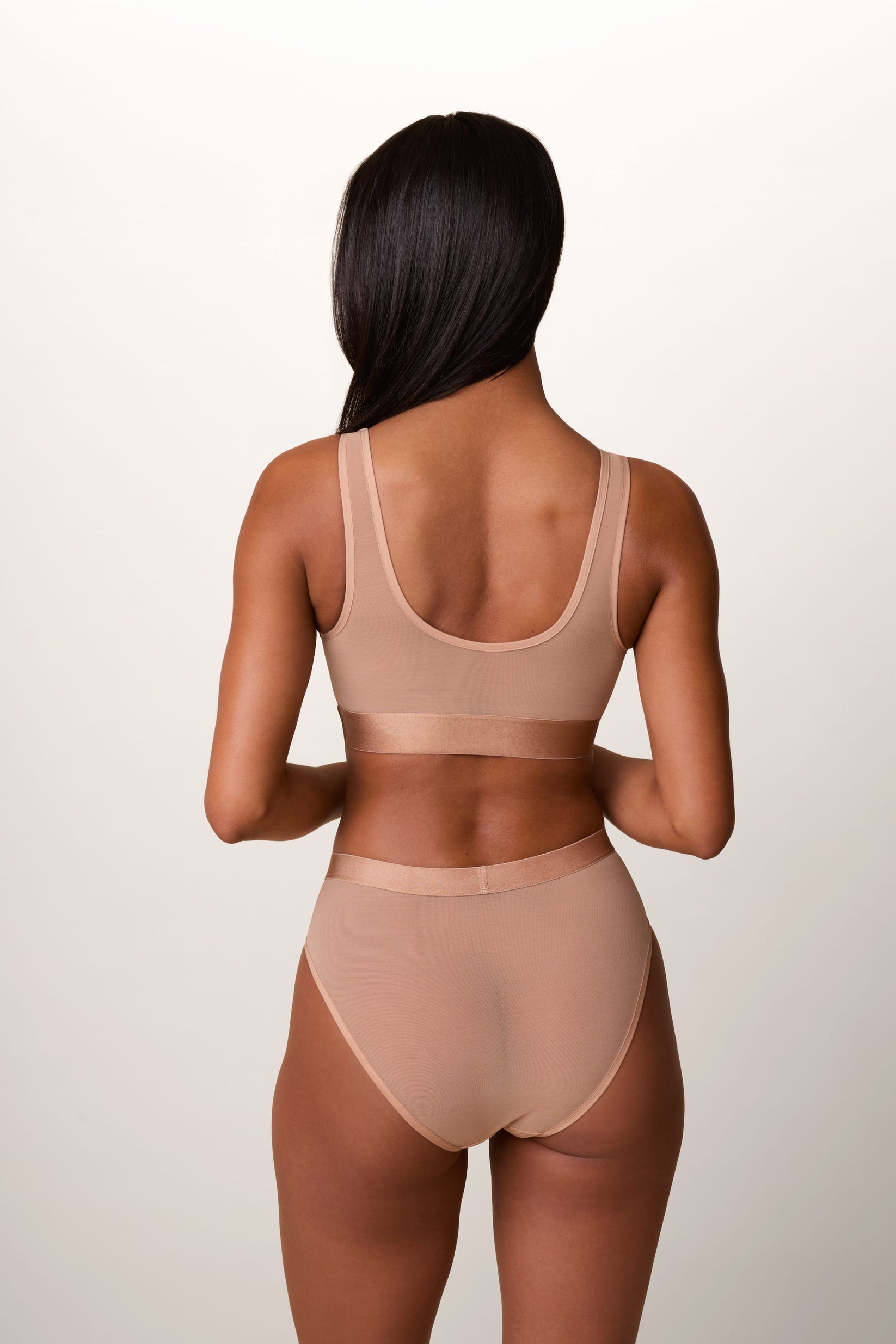 On a light studio backdrop, Ally wears the ComfortMesh™ Scoop Bralette in Taupe with the matching brief. A back view highlights the scoop-back design, sheer mesh fabric, and wide comfort band.
