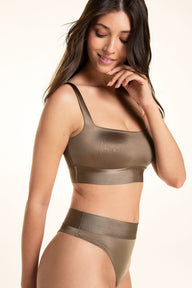On a light studio backdrop, Laura wears the Stretch Satin Square Neck Bralette and Stretch Satin Highwaist Thong in Sable, smiling and touching her chin to highlight the bralette’s silky satin finish and square neckline.